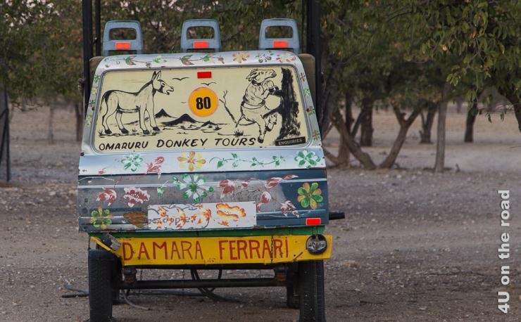 Das Bild zeigt einen Damara Ferrari, eine alte Autokarosse mit Eselsbildern auf der Heckscheibe und Blümchen. Dies ist die Verkleidung für einen Eselskarren.