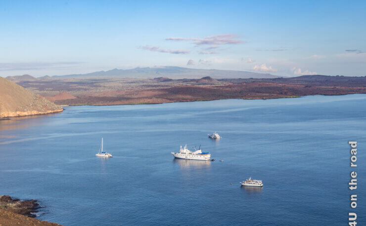 Inselhüpfen oder Kreuzfahrt auf Galapagos? Das Feature Bild zeigt die Insel Bartolomé und vier ganz unterschiedliche Schiffe, die vor der Insel parken.